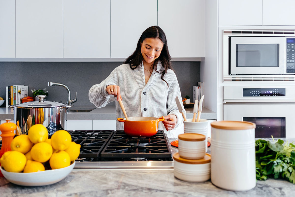 L'immagine mostra una donna mentre cucina per illustrare l'articolo che tratta la prevenzione delle tarme della farina nella dispensa